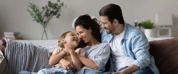 family laughing and smiling sitting on the couch